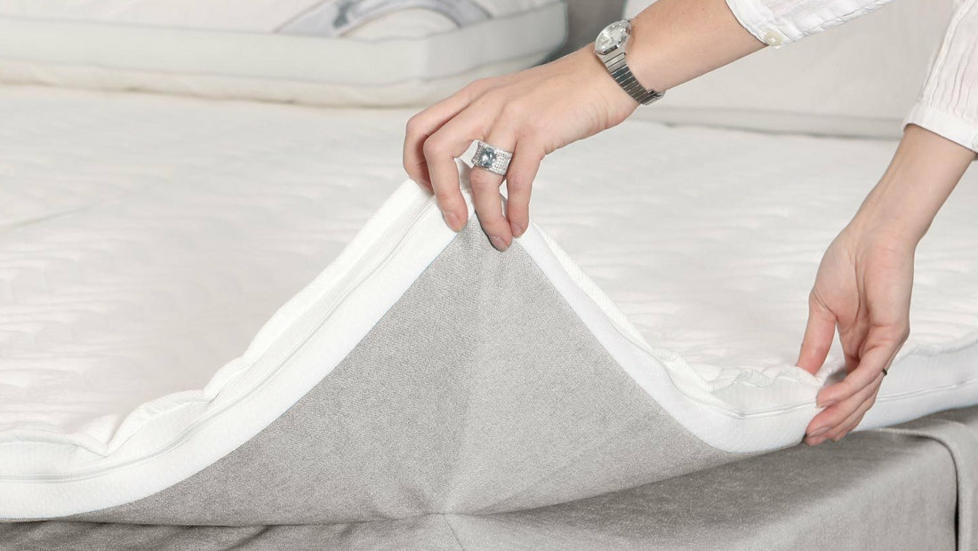 Nahaufnahme der Hände einer Person, die ein weißes Stofftextil faltet.